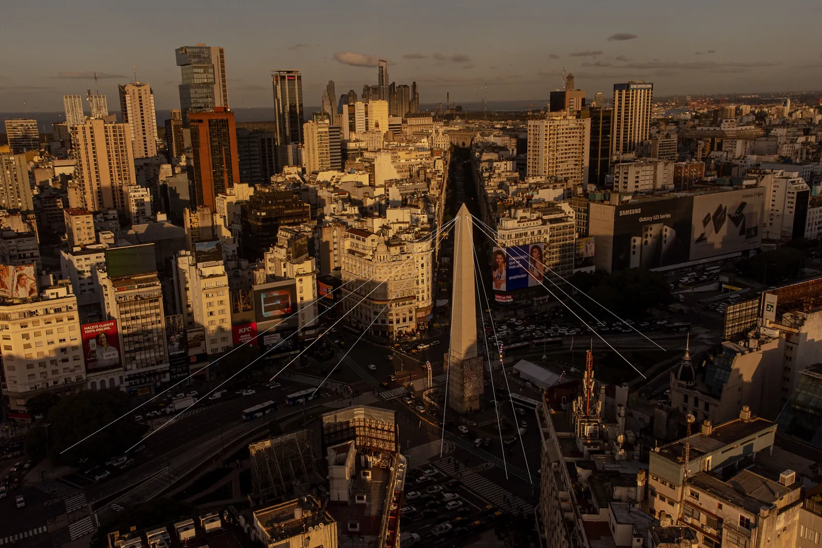 Sun sets above the obelisk where cameras are placed on the top and 9 de Julio avenue in Buenos Aires Argentina