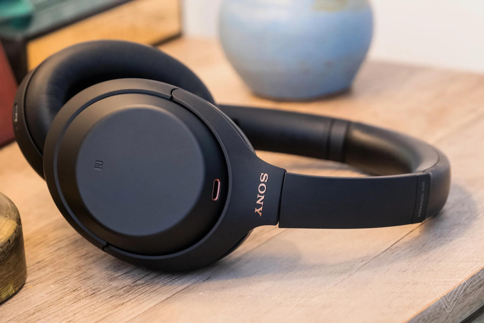 A person holding a pair of Sony WH-1000XM4 headphones.