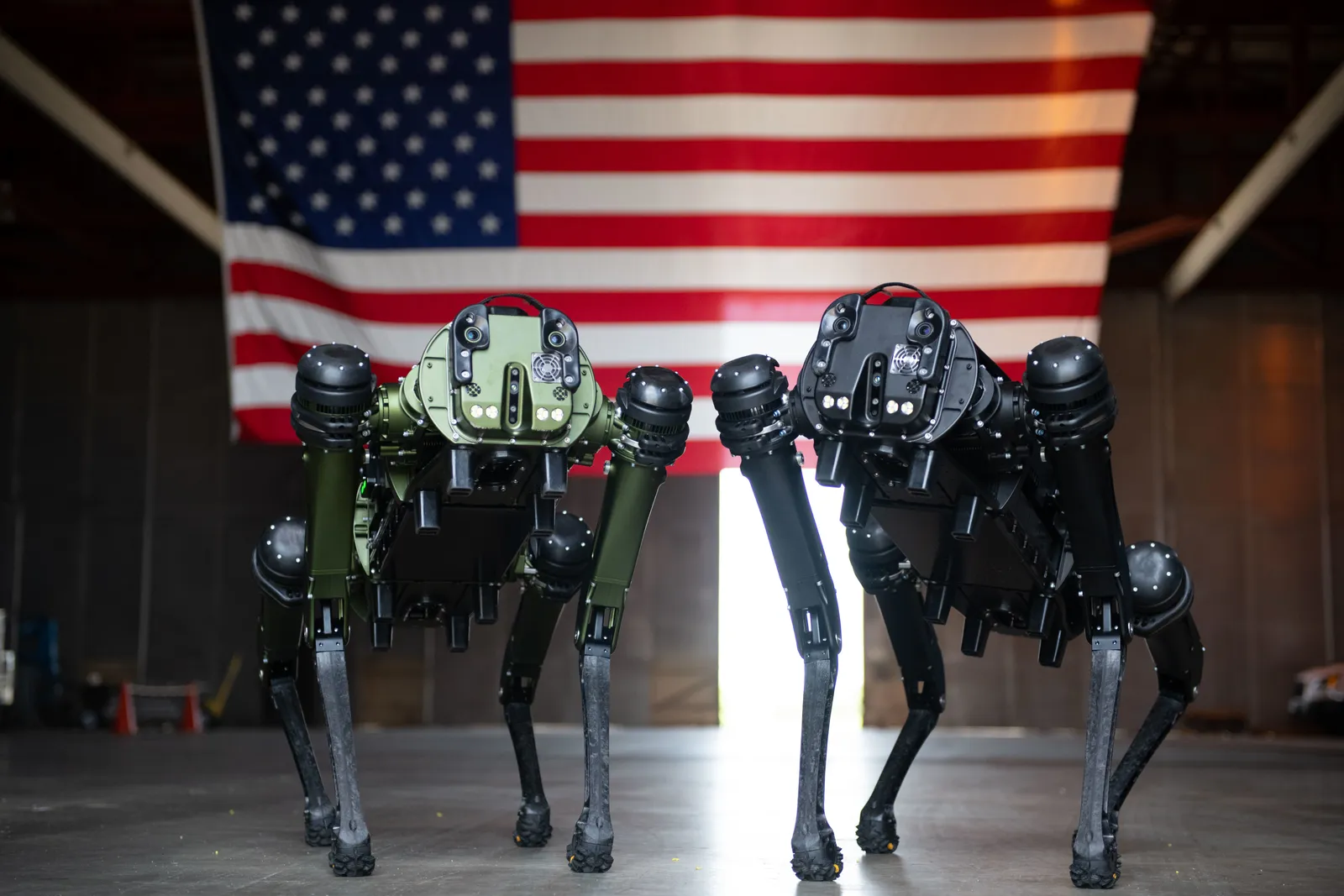 U.S. soldiers stand near a wall with a Ghost Robotic Dog