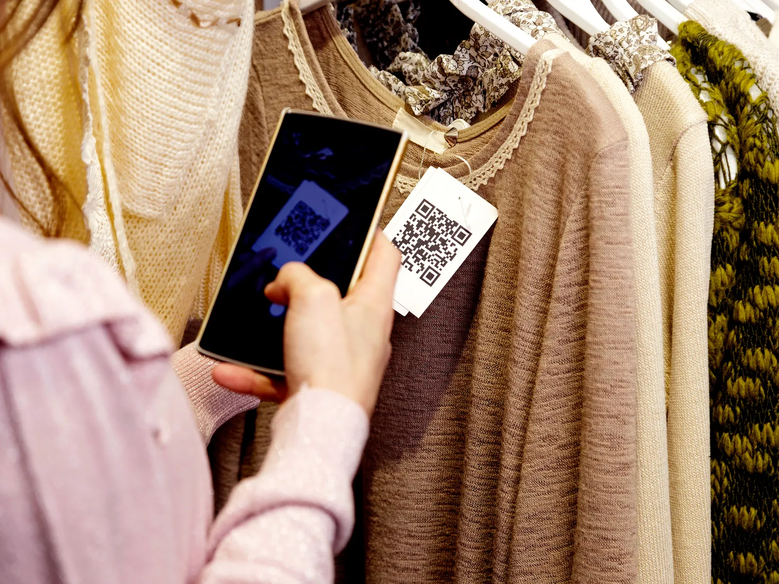 Person taking a picture of a QR code on a tag attached to clothing